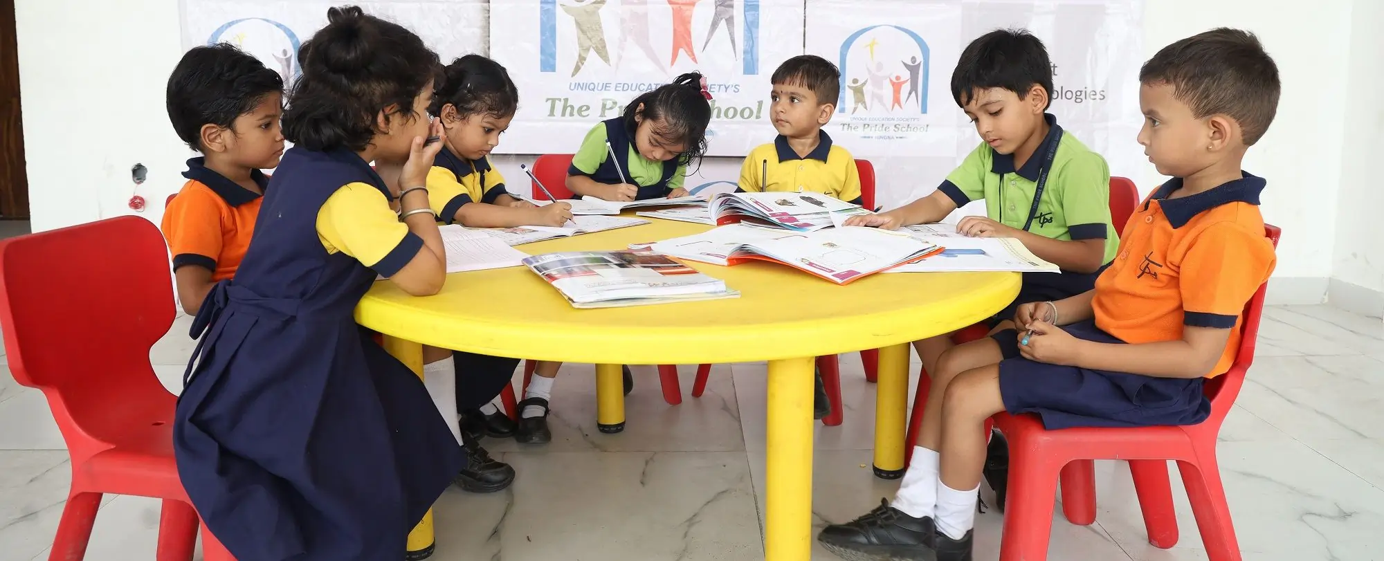 Children from Pride School engaged in collaborative learning at a table, promoting teamwork and education.
